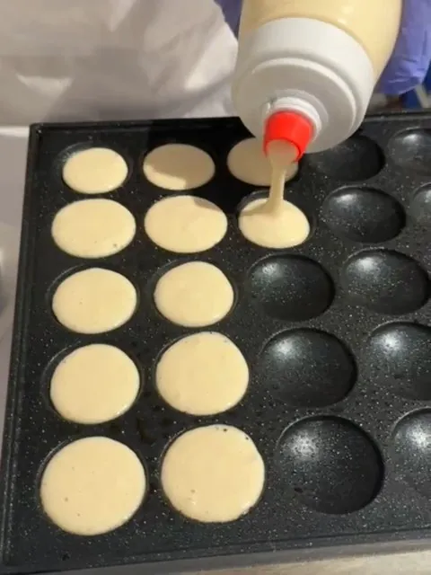 Batter being poured onto the mini pancake griddle live at an event