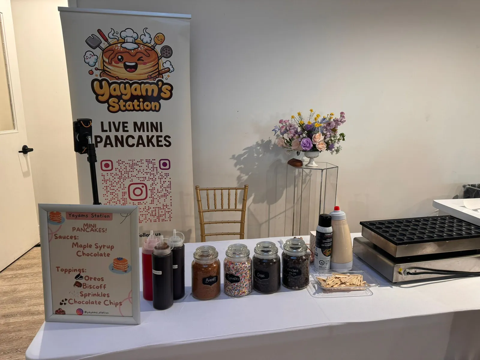 Yayam's Station live mini pancake station with toppings bar, sauces and banner set up at an event